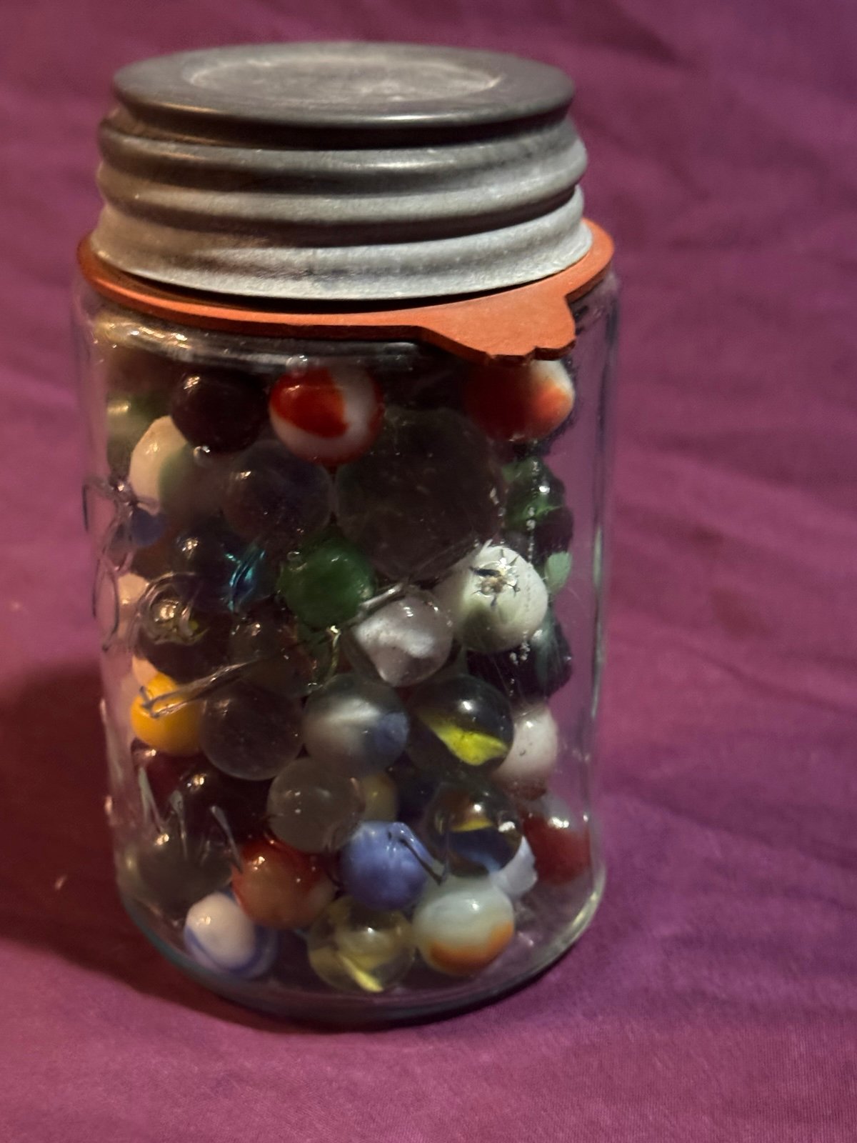 Vintage Marbles In Vintage Ball Mason Jar. Several marbles glow under Up light.