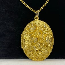 Gold tone double sided locket with ornate filigree roses