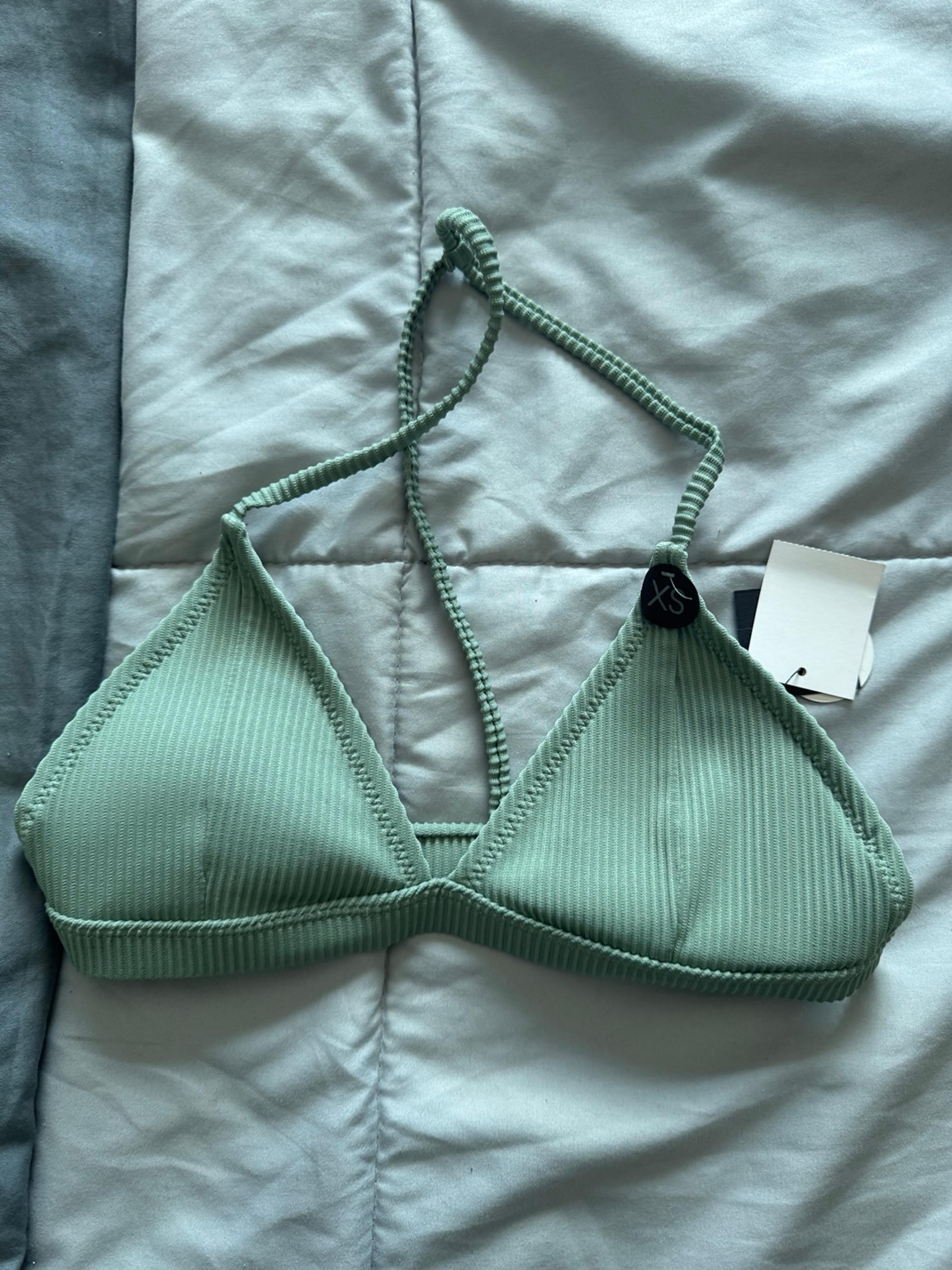 Stylish mint green ribbed bikini top with halter neck design.