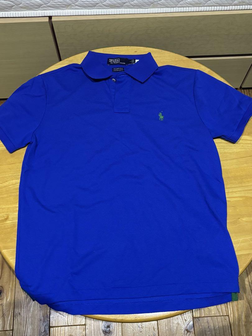 Blue polo shirt with green logo embroidery.