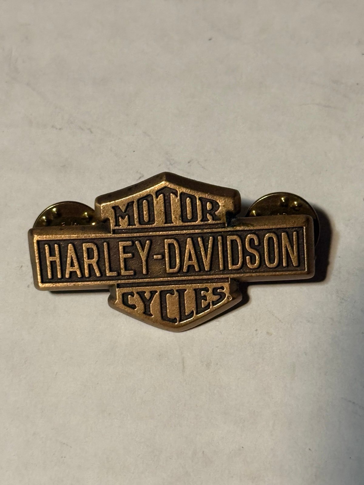vintage Harley-Davidson "Bar & Shield" brass-tone lapel vest pin.