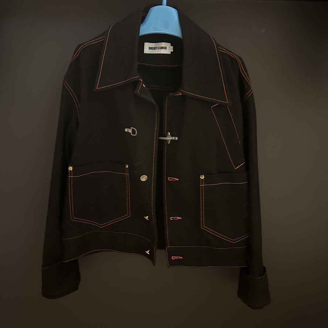 Black denim jacket with orange stitching.