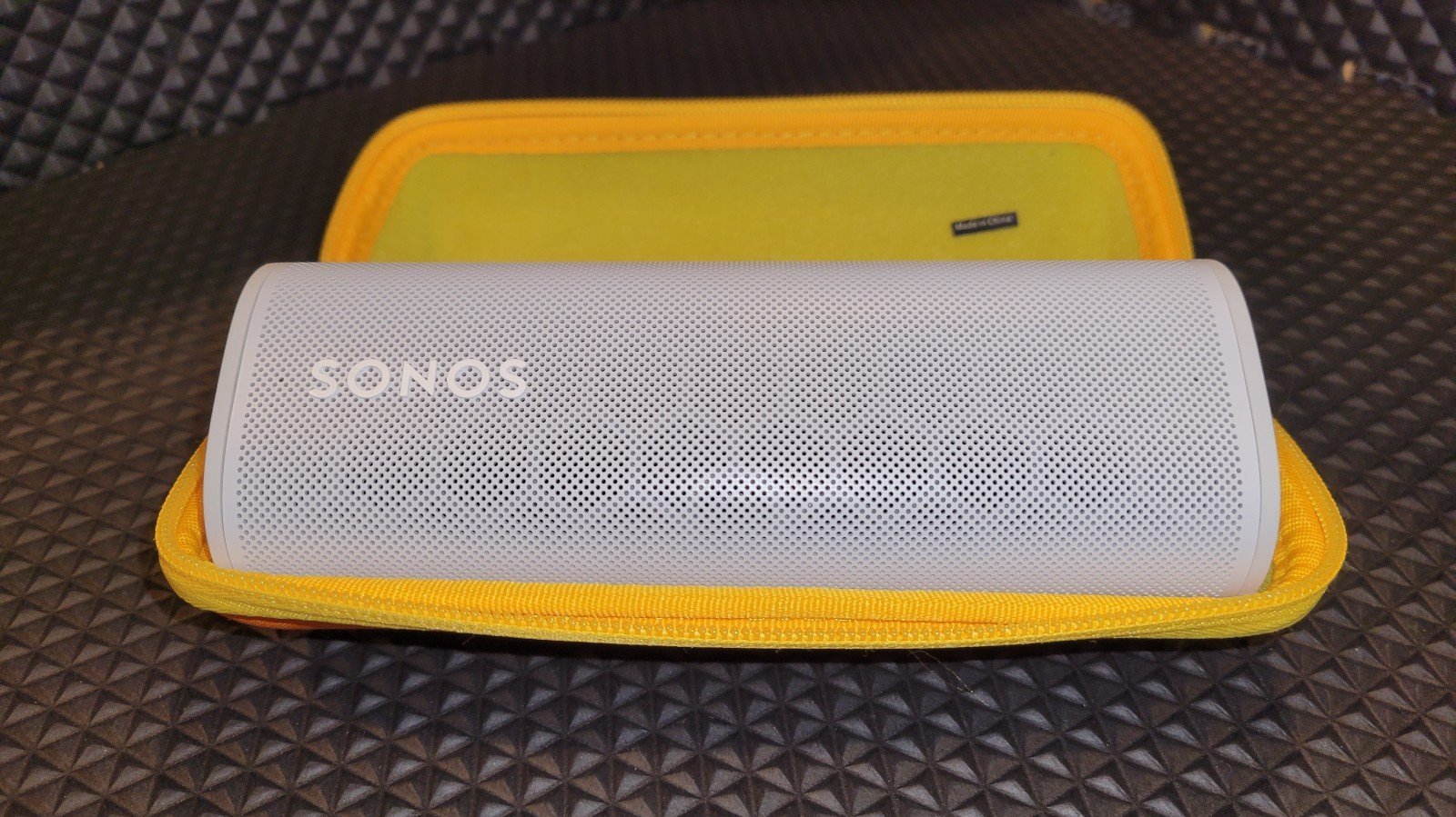 Sonos roam portable Bluetooth speaker with charger and case.