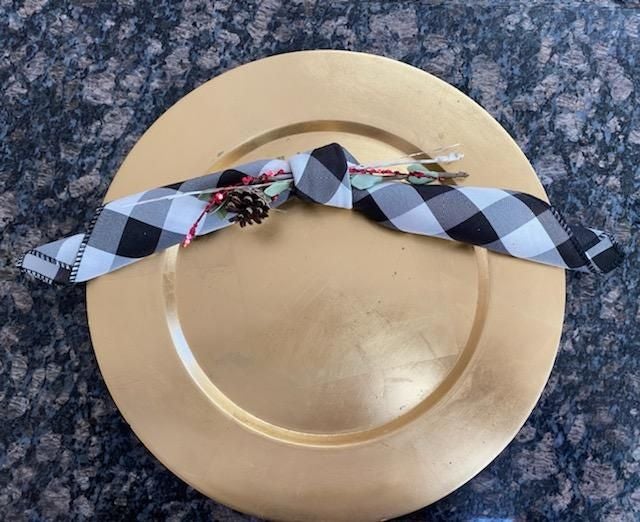 Buffalo plaid napkins that are tied with a sprig and pine cone