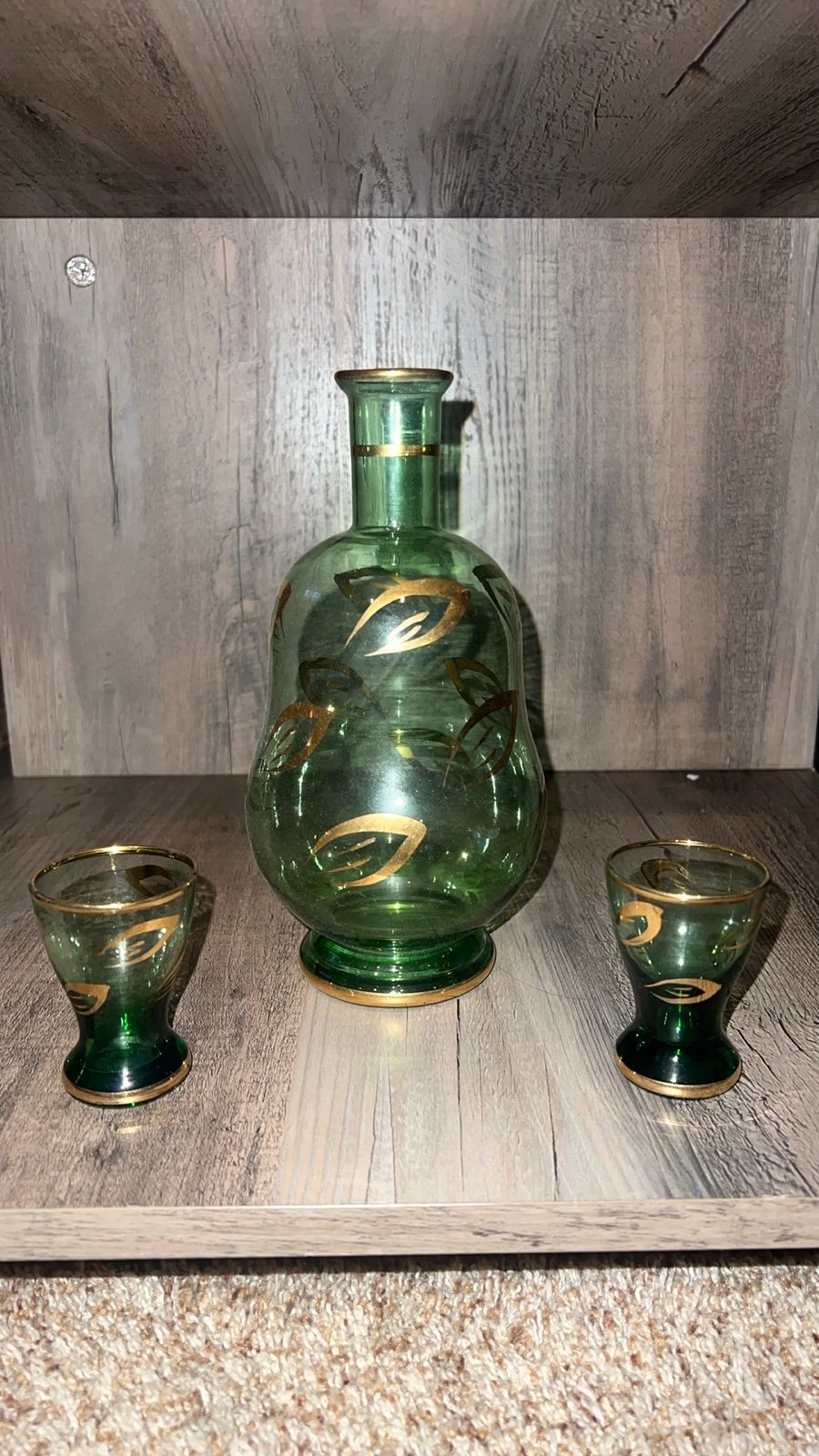 Green glass decanter w 2 shot glasses. Has good accents