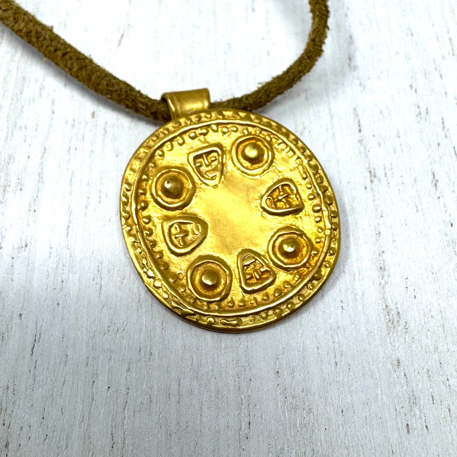 Mayan design gold tone pendant purchased in Costa Rica, on golden suede cord