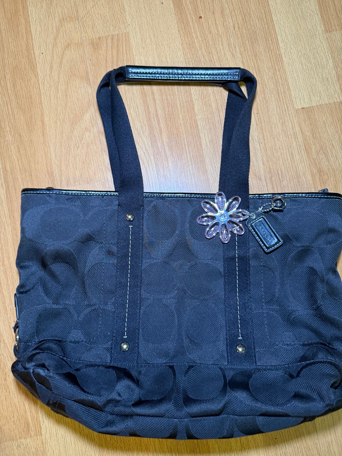 Black Coach logo canvas tote bag with adjustable straps and flower charm