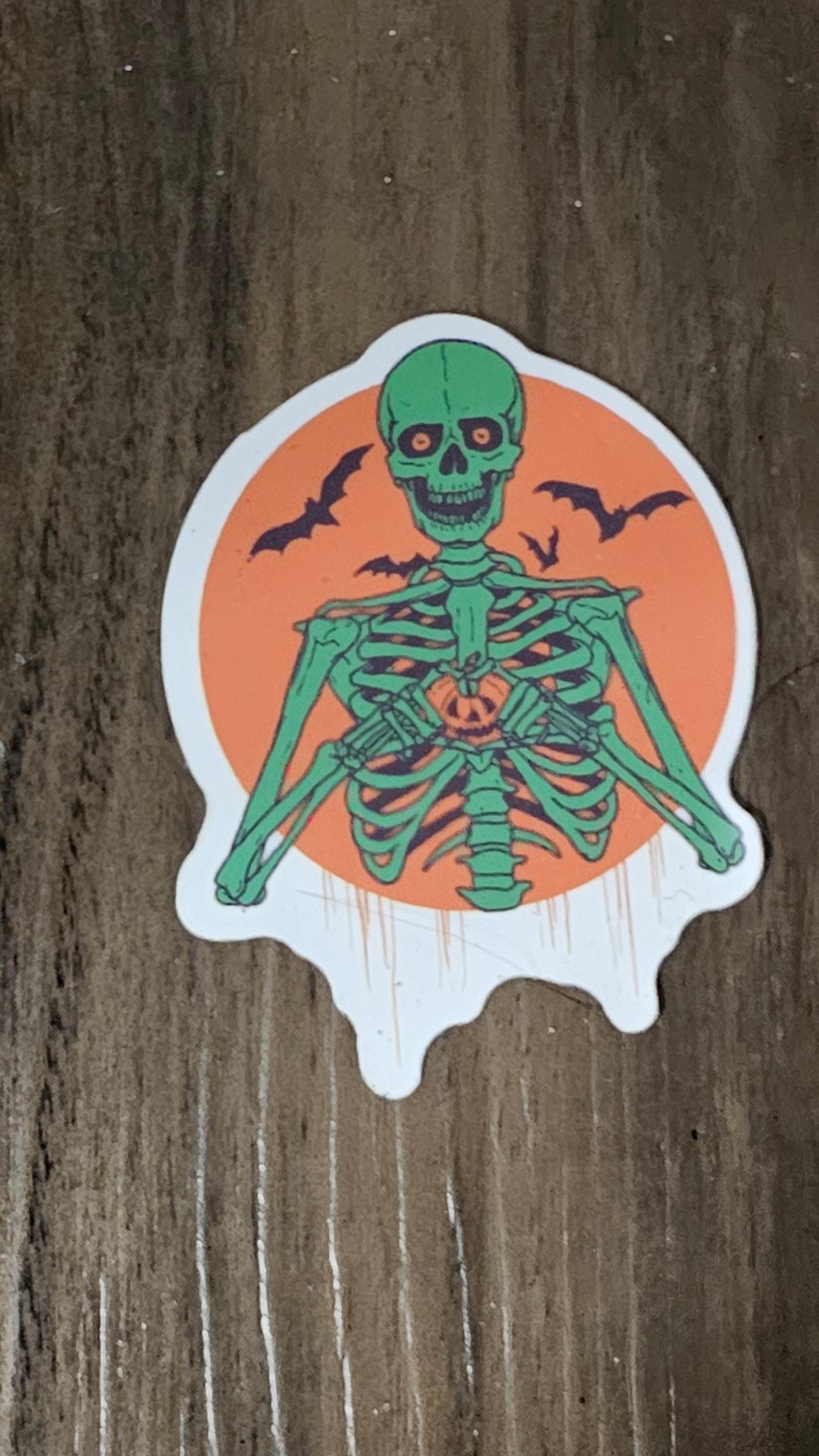 Green skeleton hold tiny pumpkin in orange sticker B7