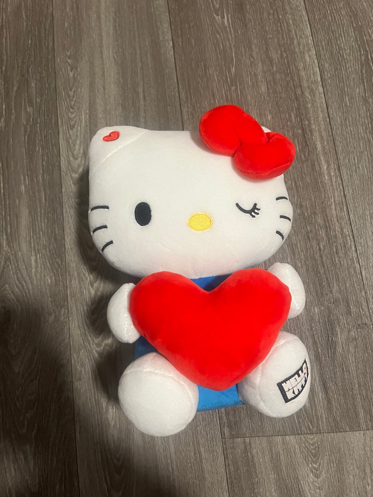 Hello Kitty winking while holding a heart plush