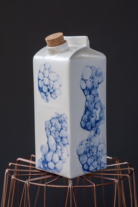 Designer's ceramic vase or milk bottle hand with white blue bubbles