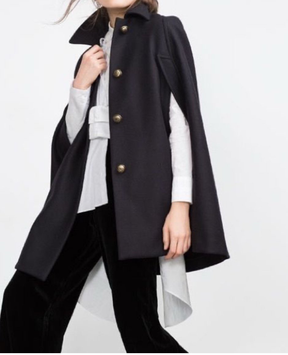 Elegant black cape jacket. Features button closure. Stylish and versatile