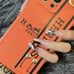 H Logo IPHONE 12 CASE SILICONE With Strap And Key Ring Orange Color