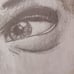 The image is a pencil sketch of a woman's face. She is looking at the viewer wit