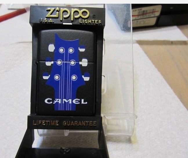NOS Zippo Joe Camel Six String Guitar and Music Note in the Black plastic case.