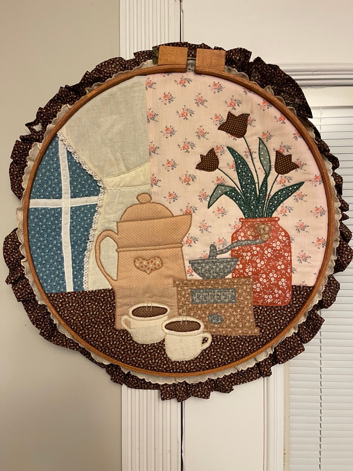 Vintage quilted wall hanging inside a wooden hoop .
