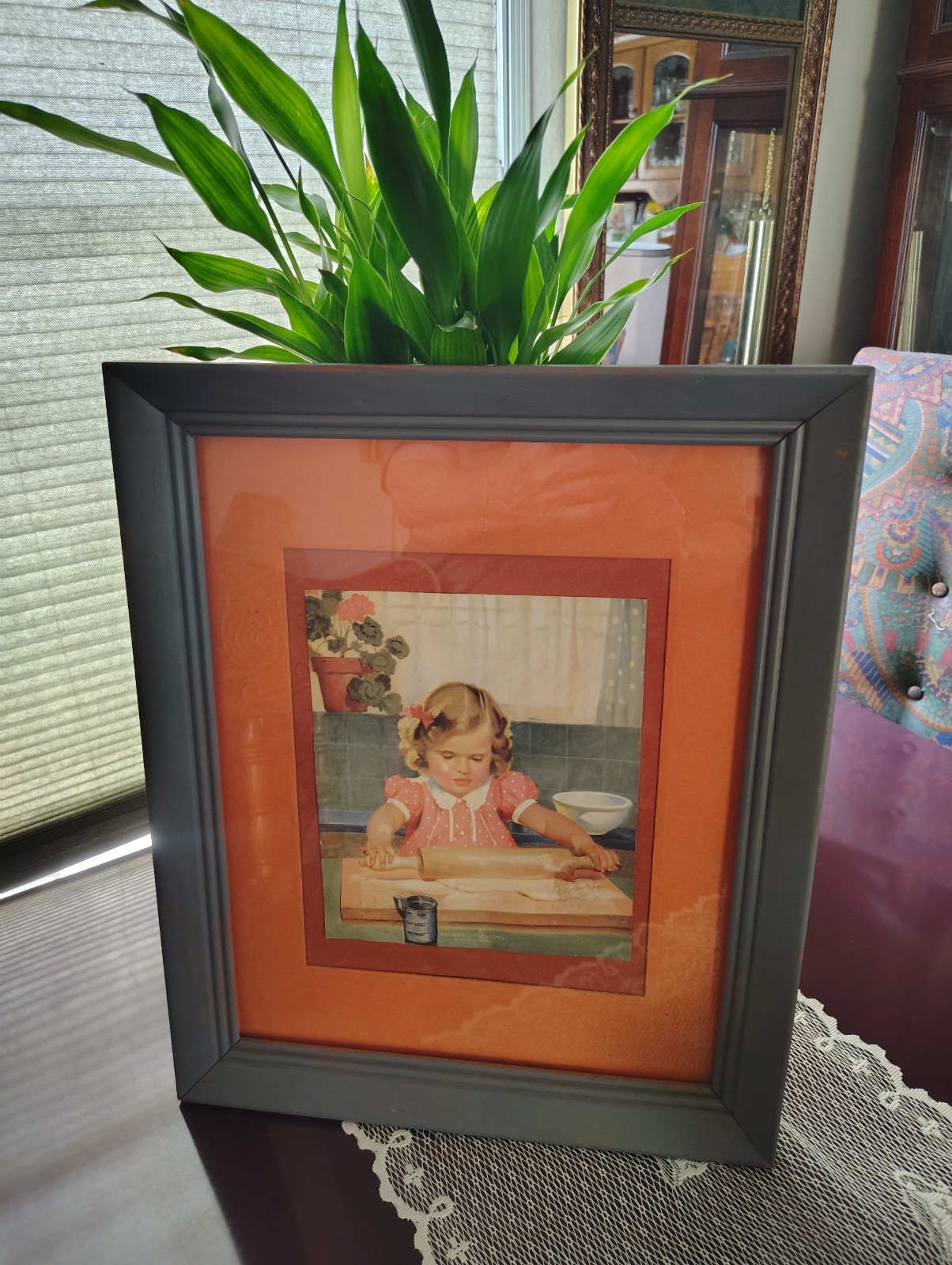 A framed print of a child rolling dough. Vintage.