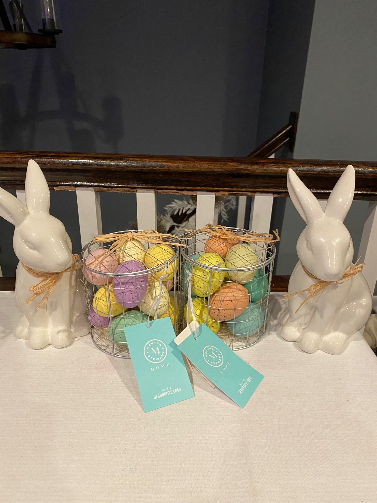 Two white ceramic bunnies & 2 wire baskets of Martha Stewart decorative eggs