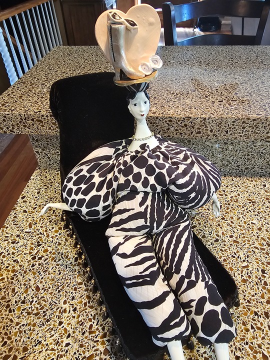 Poupee by Isabelle porcelain and millet Collectible doll with black lounge chair